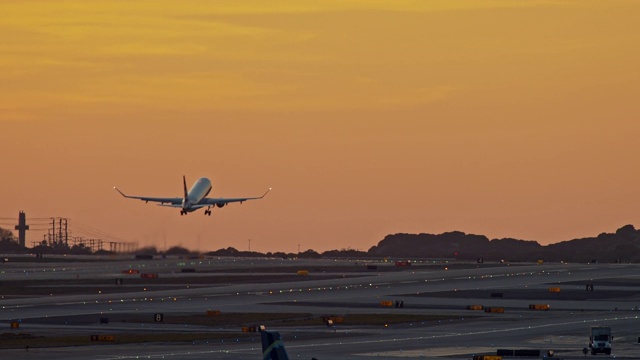 LS客机在黄昏时分从洛杉矶国际机场跑道起飞，在日落后迅速上升到橙色的天空视频素材