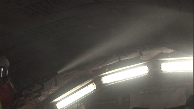 当建筑工人从软管中喷洒一种物质时，巨大的灯光照亮了隧道。视频素材