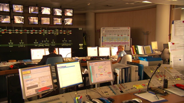 控制室工程师在地铁站的安全监视器和电子显示屏附近工作。视频下载
