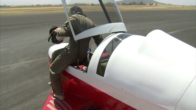 一名飞行员爬进一架实验飞机的驾驶舱。视频下载