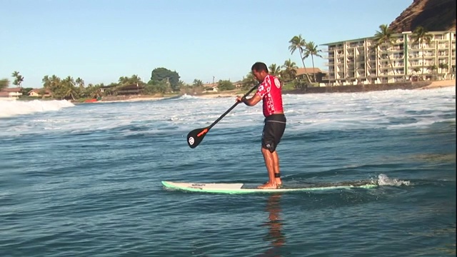 一个冲浪者把冲浪板划到海里去寻找另一个海浪。视频下载