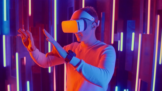 戴着VR头盔的年轻人环顾四周，惊叹不已。虚拟现实头盔。视频素材
