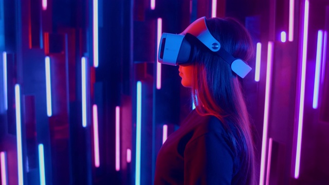 年轻女子在霓虹灯下戴上VR头盔视频素材