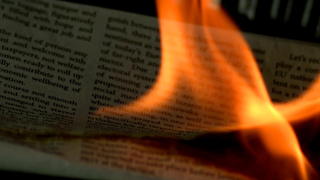 特写镜头的一份报纸燃烧在火焰中缓慢的动作。视频素材