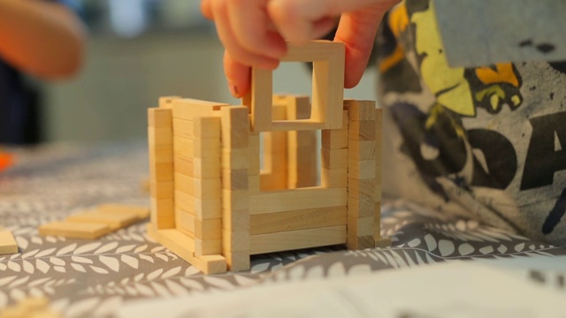 从一个木制构造器建造玩具房子的特写。视频下载