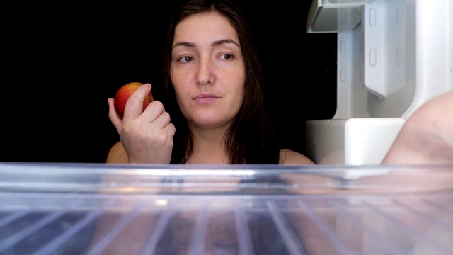 女人在寻找食物，发现巧克力和苹果微笑着视频下载