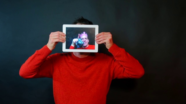 一个男人手里拿着一块平板。在平板电脑的屏幕上，一个愉快的摄影师视频下载
