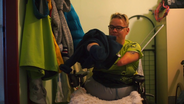 一个残疾人在公寓的走廊里脱下他的毛衣。视频下载
