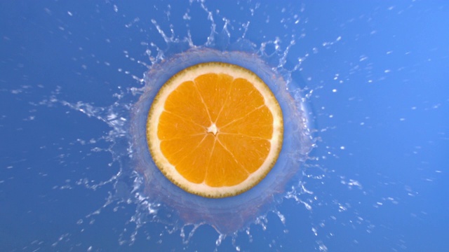 在慢动作俯视图拍摄4K，橙色新鲜水果与旋转飞溅蓝色水液体视频素材