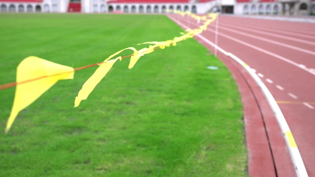 体育场的跑道。焦点是飘扬的黄旗。草皮在左边。视频下载
