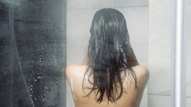 年轻的黑发女子在浴室洗澡洗头。视频素材