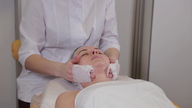专业美容师在面部清洁程序前给病人洗脸视频素材