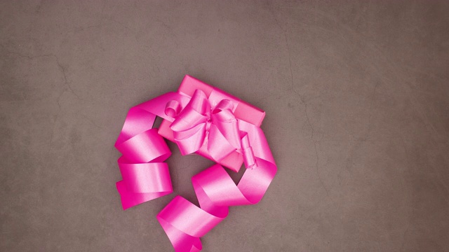 粉红色的礼物与大粉红丝带运行在灰色背景-情人节停止运动视频下载