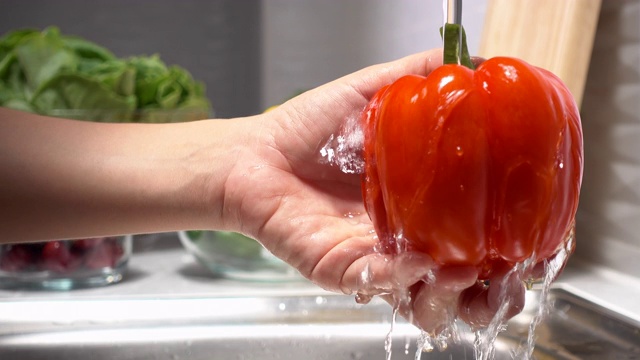一个年轻女人在厨房洗辣椒的特写视频素材