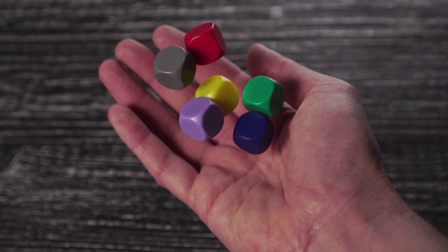玩家在一张黑色纹理的木桌上掷出6色游戏骰子视频下载