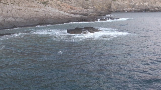 无人机拍摄到一名潜水员在靠近海洋的岩石悬崖边视频素材