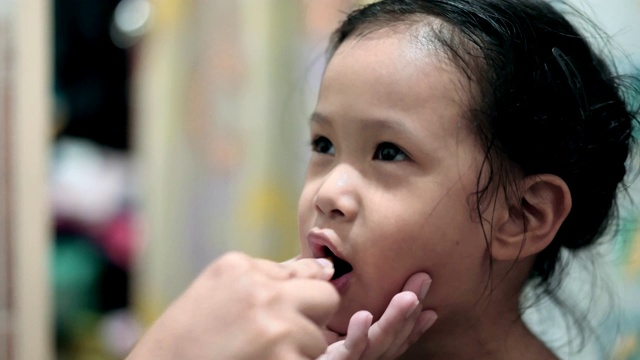 亚洲小女孩正在刷牙，她的妈妈视频素材