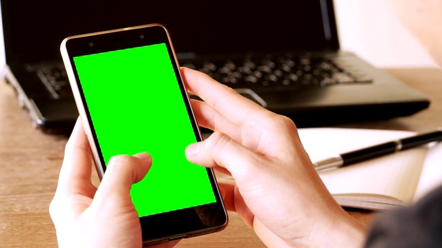 商务人士使用手机与绿色屏幕的色度键在办公桌上视频素材