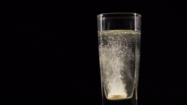 维生素C片溶解在一杯新鲜的矿物质静水中，在黑暗的背景下。起泡的液体药丸，黑色背景上有氧球视频下载