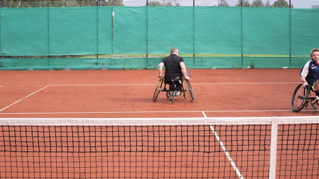 两个成年男子在户外轮椅网球上打双打视频素材