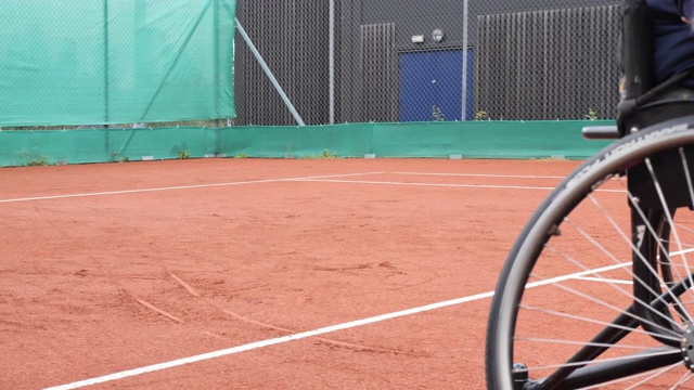 一个坐在轮椅上的成年人在户外打网球视频素材