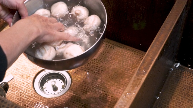 一个人用清水在碗里冲洗白蘑菇的特写视频下载
