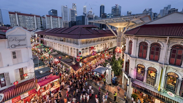 WS/TL中国农历新年期间从白天到晚上的唐人街过渡时间，展现了一个繁忙的夜市和拥挤的街道，映衬着新加坡的天际线视频素材