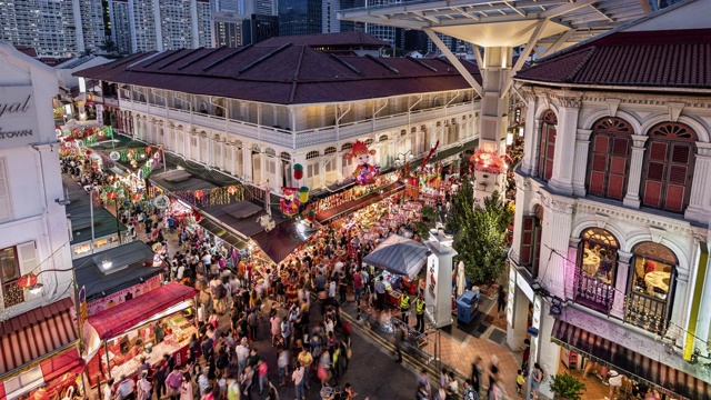 从白天到夜晚的转换/缩小/平移中国城在中国新年期间的时间流逝，展示了一个繁忙的夜市和拥挤的街道映衬着新加坡的天际线视频下载