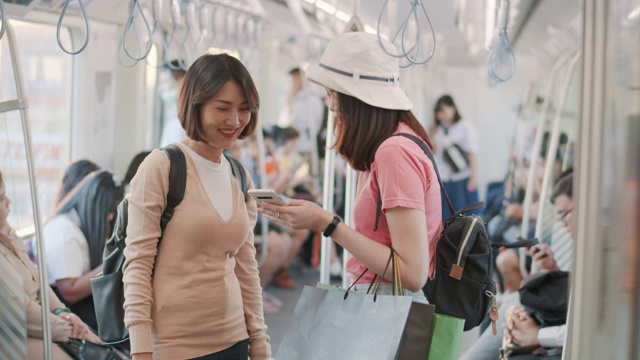 两名女游客在火车上一边聊天一边使用智能手机，慢镜头视频素材