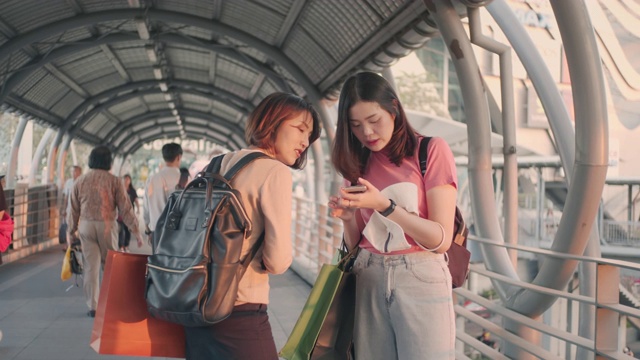 两个女游客一边聊天一边用智能手机，慢镜头视频素材