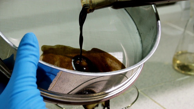 实验室内，黑色油从细管中流入金属过滤器视频素材