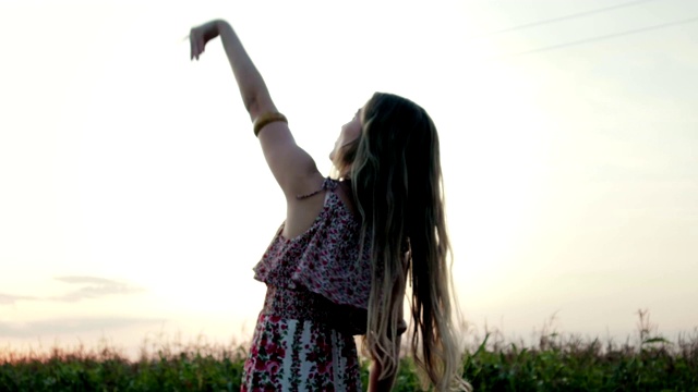 一个年轻的女子在绿色的田野里举起一架纸飞机飞向蓝天，跟随梦想的概念视频素材