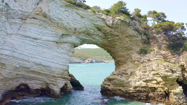 意大利加尔加诺国家公园，拱形岩石形成和海鸥在阳光明媚的田园诗般的大海上视频素材