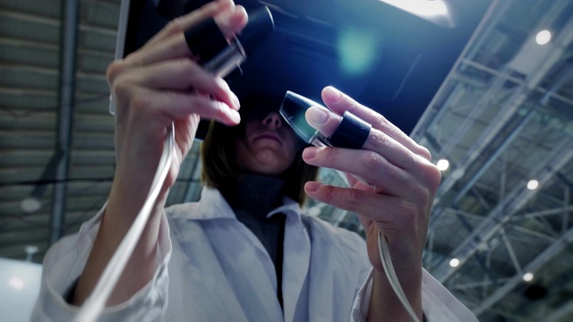 一位女外科医生在虚拟现实中给病人做手术。管理机械臂的手臂。医学新技术，创新。远程治疗癌症患者和感染者视频素材