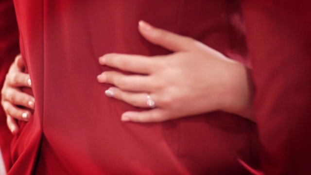 新娘与身着红色西装的新郎站在一起，温柔地拥抱视频下载