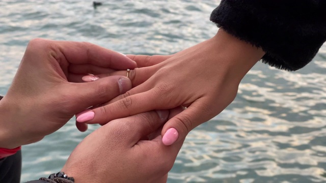 一个男人把戒指戴在他女朋友的手上。慢动作和流畅的构图为情人节拍摄。视频下载