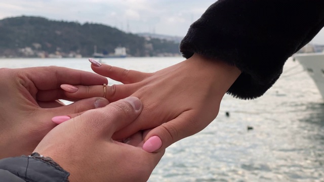 在海边，一个男人把戒指戴在女朋友的手上。特写镜头视频下载