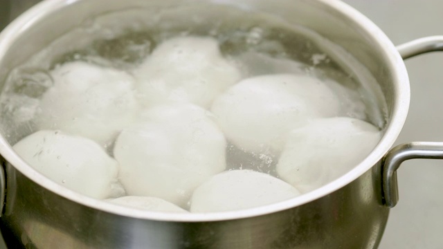 8个煮鸡蛋在沸水中的特写。4 k视频素材