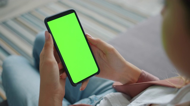 女性手握大现代智能手机与空白绿色屏幕在家里视频素材