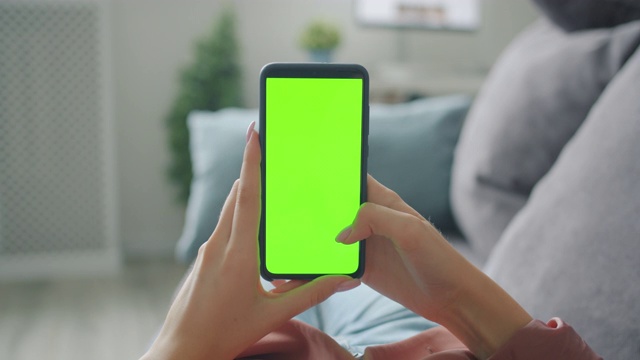 女士的手在家里触摸绿色智能手机屏幕的慢动作视频素材