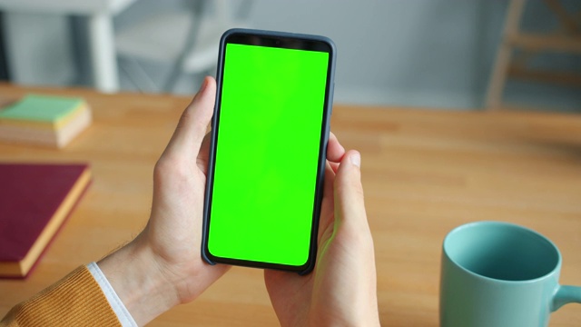 男性手握色度键绿色屏幕智能手机在办公室的特写视频素材