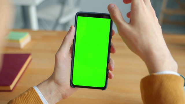 人类男性的手触摸智能手机与绿色模拟屏幕的特写视频素材