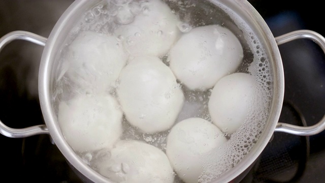 8个白色鸡蛋放在一锅沸水里的特写。4 k视频素材