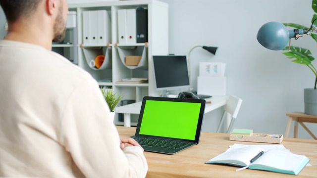 商人看绿色屏幕彩色键笔记本电脑在现代办公室工作视频素材