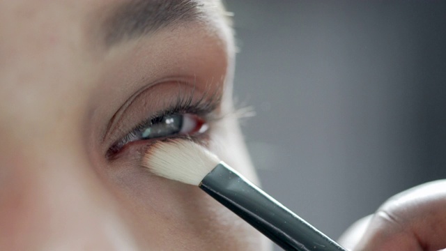 一个特写，一个美容师正在用刷子刷模特的眼睑视频下载