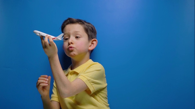 小男孩在蓝色背景上玩着玩具飞机视频素材