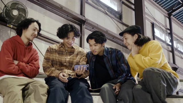 一群日本男孩在智能手机上看视频(慢镜头)视频下载