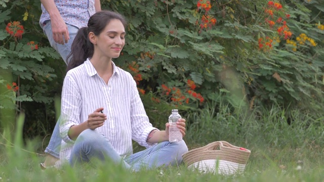 情侣们在公园里野餐时聊天喝水。视频素材