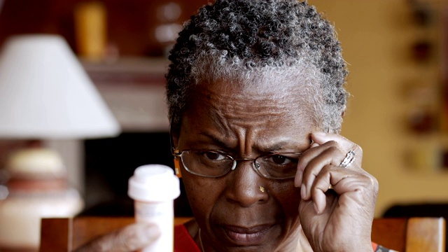 非裔美国老年妇女戴眼镜读她的处方瓶视频素材