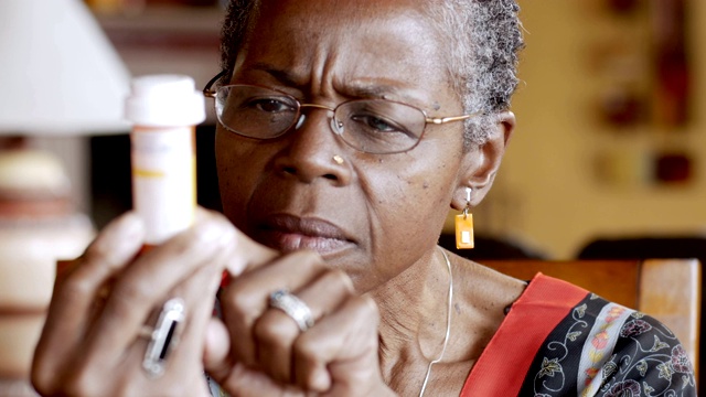 非裔美国老年妇女试图阅读她手中的药瓶标签视频素材